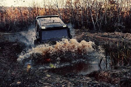 4x4 concept. SUV or offroader on mud road. Large rocks on the road extreme travel adventure in...