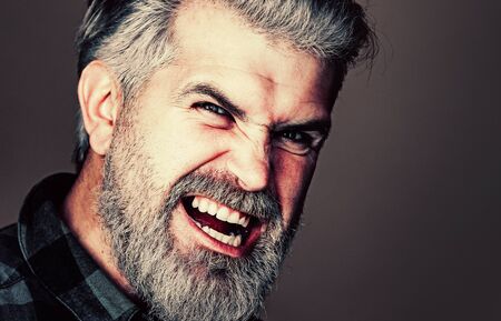 Angry Man. Portrait of a happy man over gray background. Fashion style portrait of handsome guy. Handsome young man on grey background looking at camera.の写真素材