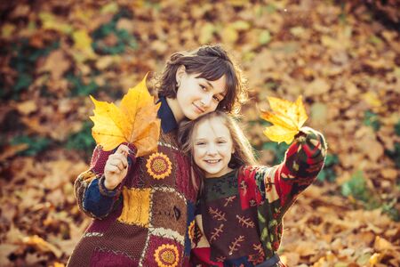 Fallen yellow leaves. Outdoor. Inspired girls surrounded by vivid foliage. Autumn girls enjoy fallen leaves. Fall time. Portrait of two beautiful young girls outdoors in autumn.の写真素材
