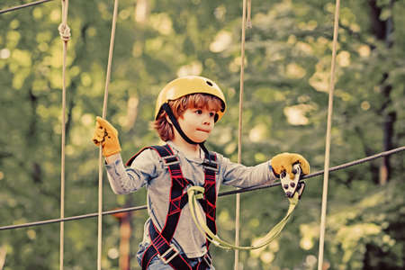 Adventure climbing high wire park. Cute school child boy enjoying a sunny day in a climbing adventure activity park. Child playing on the playgroundの写真素材