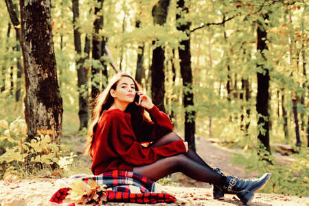 Retouched and natural light. Romantic Autumn Woman Model. Romantic Young Woman on Natural Background Outdoors. Copy space for text. Autumn woman having fun at the park and smilingの写真素材