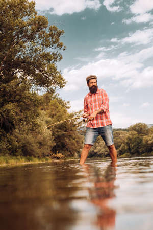 Fishman crocheted spin into the river waiting big fish. Just do that only. Luxury life concept. Perfect weekend. Keep calm and fish on. Fly fishing. Fisherman with rod and fish.の写真素材