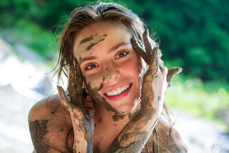 Dirty girl. Beautiful woman with facial mask. Funny girl making black clay mask. Spa Outdoor.の写真素材