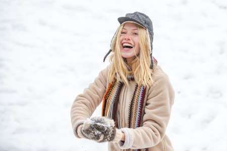 Happy woman holds snowball in hands. Portrait of a happy girl in the winter.