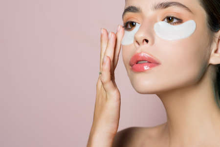 Close up of young woman face with eye patches. Mask under eyes. Beautiful female with natural makeup...