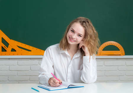 Portrait of smiling teenager girl over blackboard, friendly laughing. Cute college female student in hight school.の写真素材