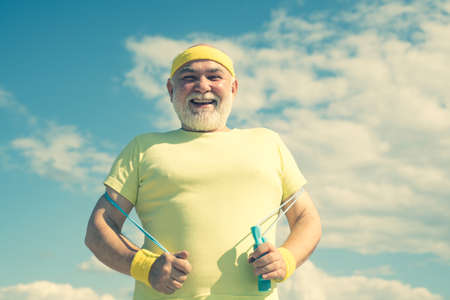 Best cardio workout. Senior man is doing fitness training. Grandfather sportsman on blue sky...