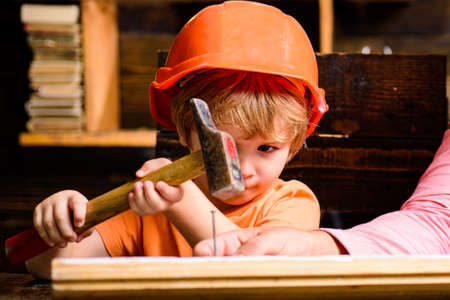 Funny little repairman with hammer. Kids construction worker. Child use a hammer to nail.の写真素材