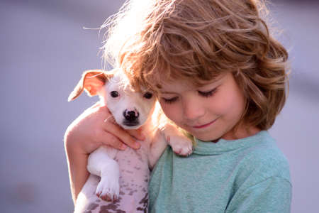 Happy child and dog hugs her with tenderness smiling. Little boy hugging puppies. Close up, copy...