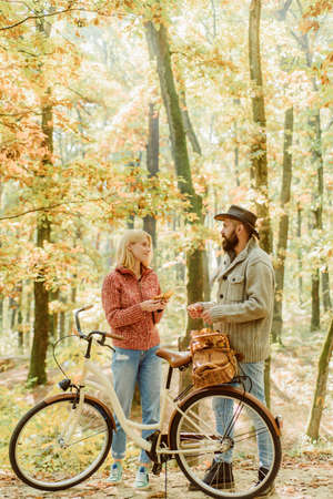 Romantic couple with bicycle spending weekend in autumnal park. Happy smiling tender woman and...