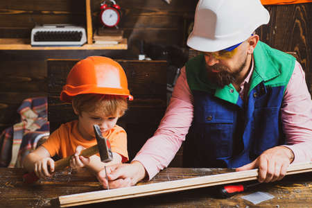 Father and son working with a hammer. Future kids profession. Construction of dad and boy in the garage.の写真素材