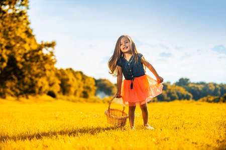 Sweet little girl in a autumn meadow. Cute child girl having fun in park. Beautiful autumnal fall time in nature.の写真素材