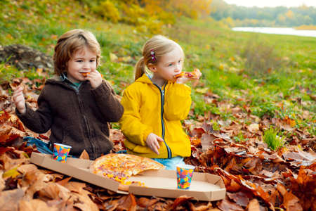 Children eating pizza on autumn fall time in nature.の写真素材