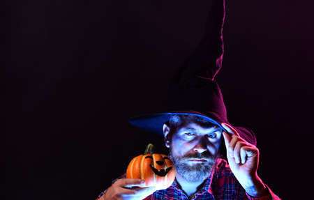 31 october. Evil witcher with red hair and a beard in a black cloak reading a book of spells. Make...