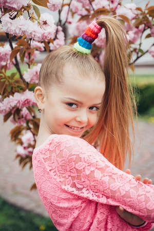 Spring teenager girl in fragrant pink flowers in summer blossom park. Kid with flower on Easter.の写真素材