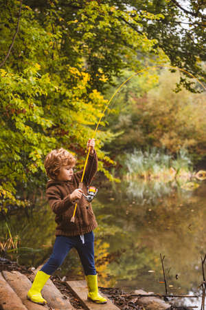 Photo of kid pulling rod while fishing on weekend.の写真素材