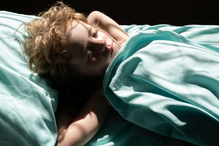 Calm child sleeping in comfortable bed lying on soft pillow orthopedic mattress, cute kid resting...