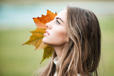 Close-up portrait of beautiful autumn woman outdoors.