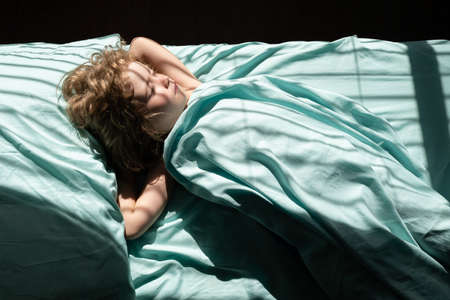 Child sleeping on bed in bedroom at home.