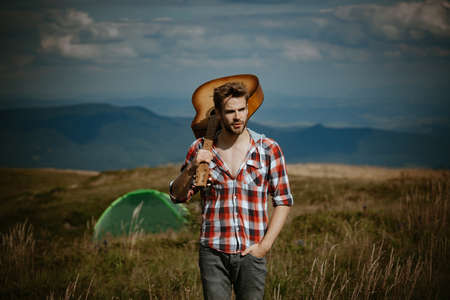 Nature, summer, youth culture and people concept. Young hippie man hold guitar on nature outdoors. Hipster guy relaxing on a summer day.の写真素材