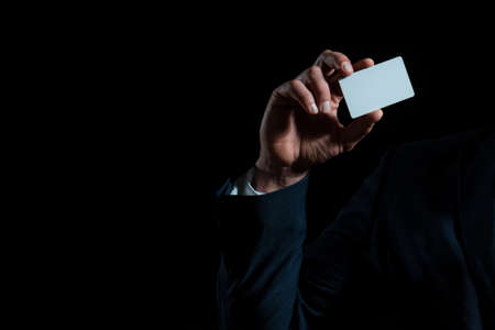Hand holds a credit card. Male hand holding blank plastic credit card on black isolated studio background, copy space. Credit-Card, Buying, Banking services.の写真素材