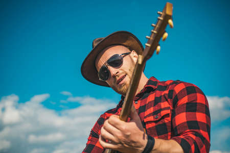 Young man plays guitar at sky.