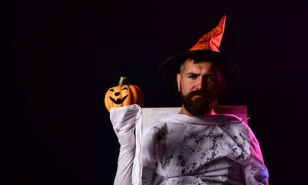 Halloween man with pumpkin in darkness. Wizard, sorcerer, warlock. Halloween man with smile on dark...