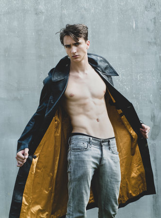 Fashion male model. Portrait of gorgeous fashion man wearing leather coat, black clothes, trendy hipster boy. Handsome guy with confident face.の写真素材