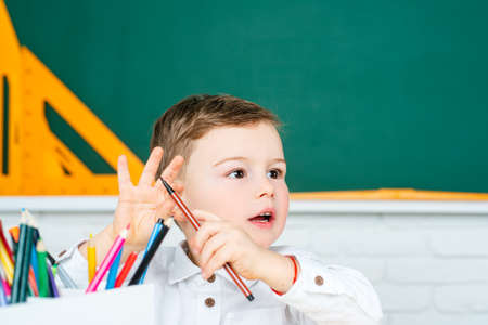 Kid indoors of the class room with blackboard on a background. Back to school.の写真素材