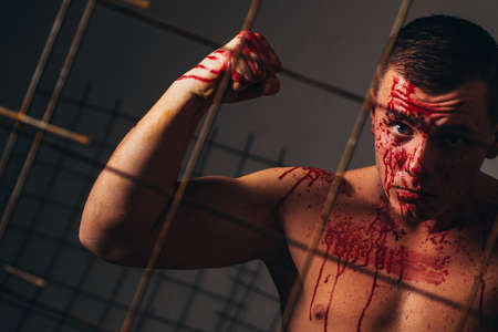 Murderer brutal aggressive guy. Halloween concept. Aggressive person. Injured soldier. Pain and injury. Aggressive monster. Body soiled blood. Prison for monster. Psycho mad man. Psychic diseaseの写真素材