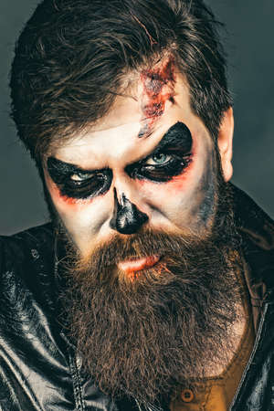 Happy Halloween - handsome vampire isolated on dark background. Halloween party and holiday concept. Vampire man with bloody eyes. Scary hipster with beard in Halloween hat.の写真素材