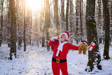 Excited Santa in the winter field. Santa Claus on Christmas Eve is carrying presents to children in a bag.の写真素材