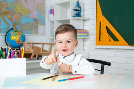 Surprised cute child, writing in notebook using pencil.の写真素材