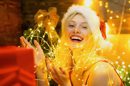 Sexy Santa woman posing on vintage wooden background. Night background with a sparkler. Christmas...