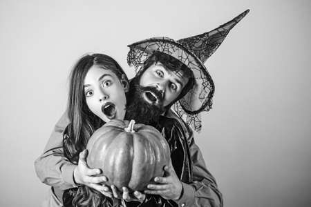Halloween couple embracing. Best friends celebrated Halloween. Halloween surprised woman and handsome bearded man in Halloween hat and costume holding pumpkin.の写真素材