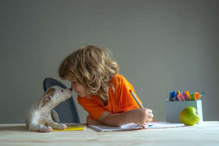 Cute child and dog playing at home. Back to school. A Cute little boy with pet puppy doing homework.の写真素材