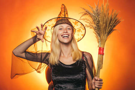 Sexy woman on orange background. Background decorated for Halloween. Happy halloween. Halloween party and funny Pumpkin. Happy Halloween Quotes and Sayings. Magic hat. Skeleton posing with Pumpkin.の写真素材