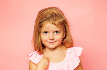 Handsome little girl in preparing for Autumn. Kid having fun with Leaf fall. Autumn sale. Pretty little child holding gold leaf on pink background. Autumn concept.の写真素材