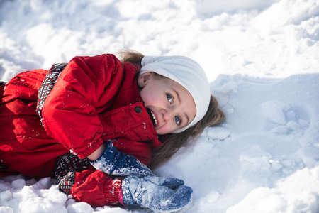 Winter child girl laying in the snow.の写真素材