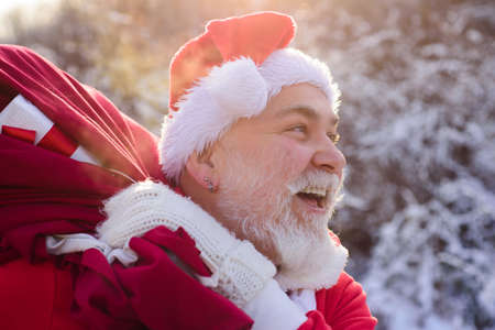 Santa Claus coming to the winter forest with a bag of gifts, snow landscape.の写真素材