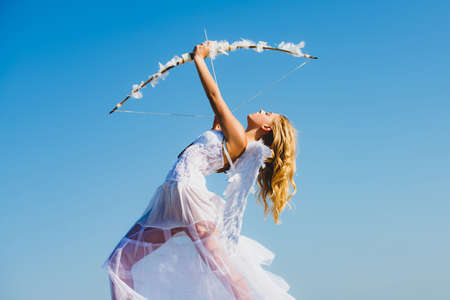 Angel teen with feather white wings. Cupid shoots a bow.