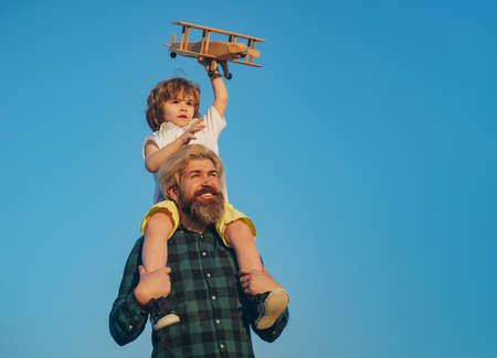 Happy father giving shoulder ride on his shoulders. Father and son together. Boy child is sitting on daddy shoulder piggyback while the flight.の写真素材