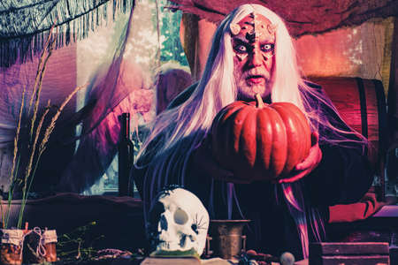 Devil in wicked witch hat. Devil man with skull with bloody eyes. Bearded man dressed like Halloween monster. Happy Halloween.の写真素材