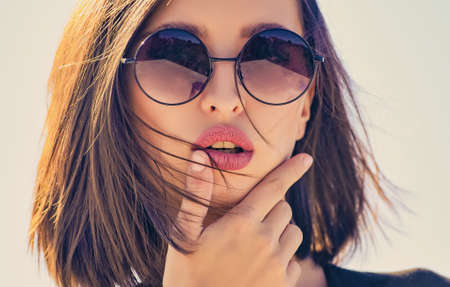 Female fashion model posing with sunglasses. Close-up portrait of a beautiful charming young...