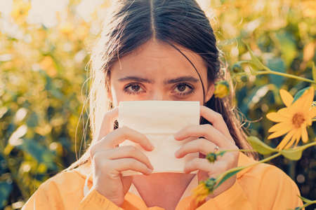 Young woman is going to sneeze. The girl suffers from pollen allergy during flowering and uses...