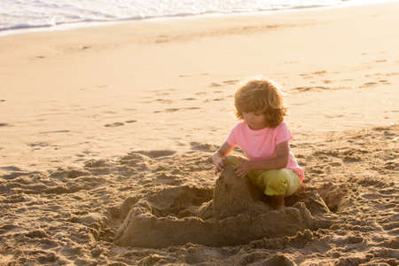 Child play with sand on summer beach. Kid build sandcastle. Kids summer vacation.の写真素材