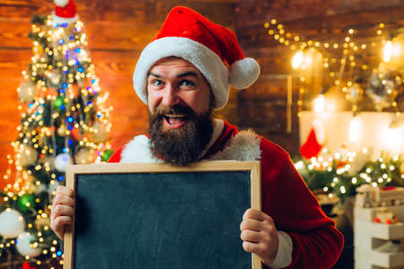 New year fashion clothes. Theme Christmas holidays and winter new year. Men in winter clothes. Happy Santa dressed in winter clothing think about Christmas near Christmas tree.の写真素材