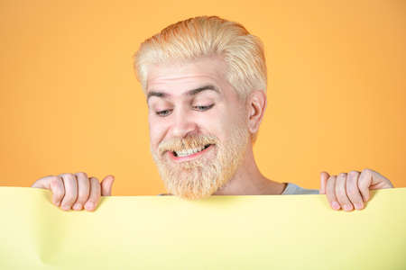 Man holding card, man with banner, isolated yellow background, man showing empty card.の写真素材