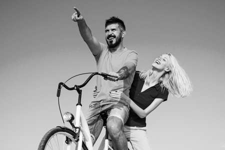 Young hippie couple on sky blue background. Beautiful smiling girl and bearded hipster man is riding...