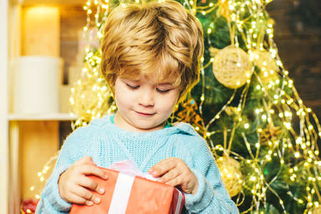 Happy child with Christmas gift. Portrait of Santa kid with gift looking at camera. Kid having fun...